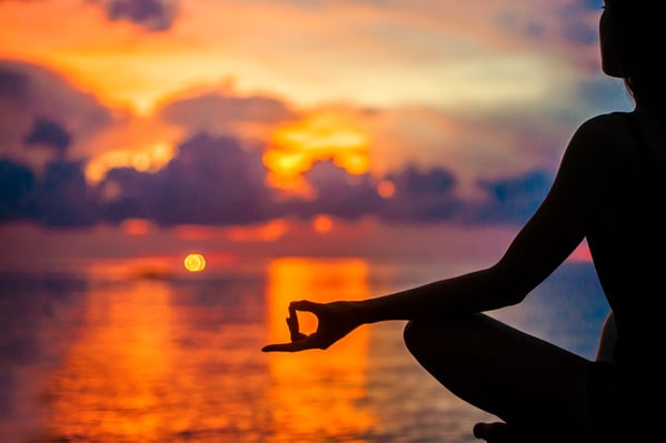 Woman meditating, relaxing in yoga pose at sunset, zen meditation